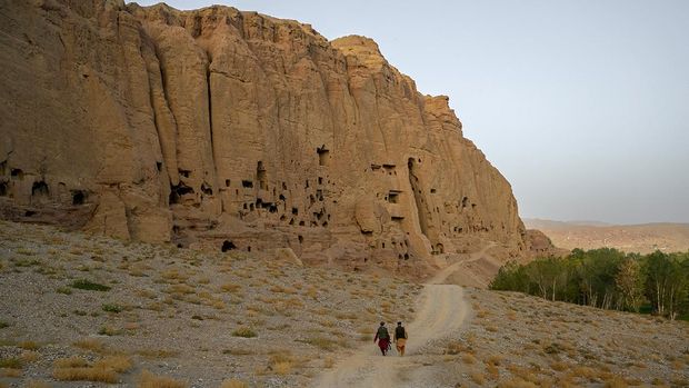 Members of Taliban walk past the site where the Shahmama Buddha statue once stood before being destroyed by the Taliban in March 2001, in Bamiyan province on October 2, 2021. (Photo by BULENT KILIC / AFP)