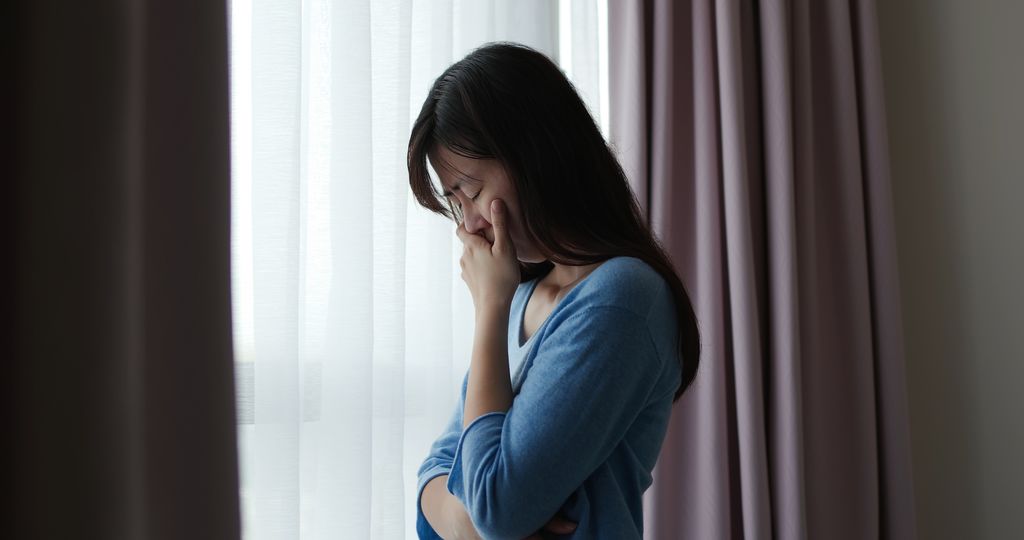 asian depression sad woman is standing by windows alone at home and thinking negative thoughts
