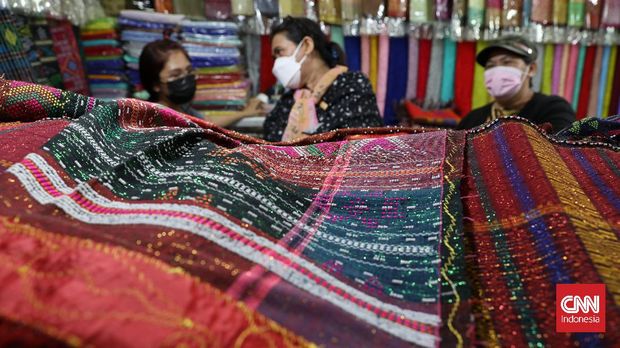 Pembeli memilih kain ulos di pasar Senen, Jakarta, Selasa, 12 Oktober 2021. Kain tenun khas Sumatera Utara ini sebagai pelengkap pakaian saat acara adat dan kematian suku Batak. CNNIndonesia/Safir Makki