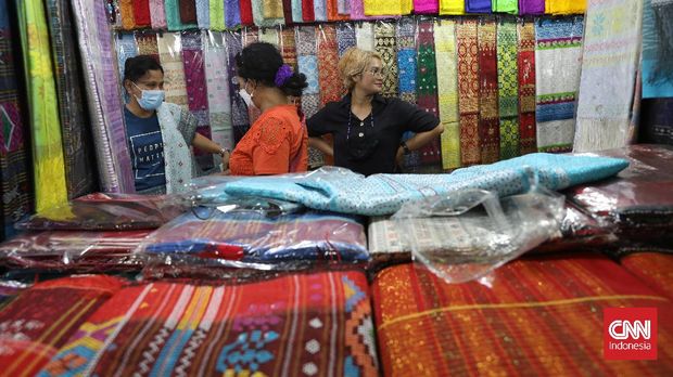Pembeli memilih kain ulos di pasar Senen, Jakarta, Selasa, 12 Oktober 2021. Kain tenun khas Sumatera Utara ini sebagai pelengkap pakaian saat acara adat dan kematian suku Batak. CNNIndonesia/Safir Makki