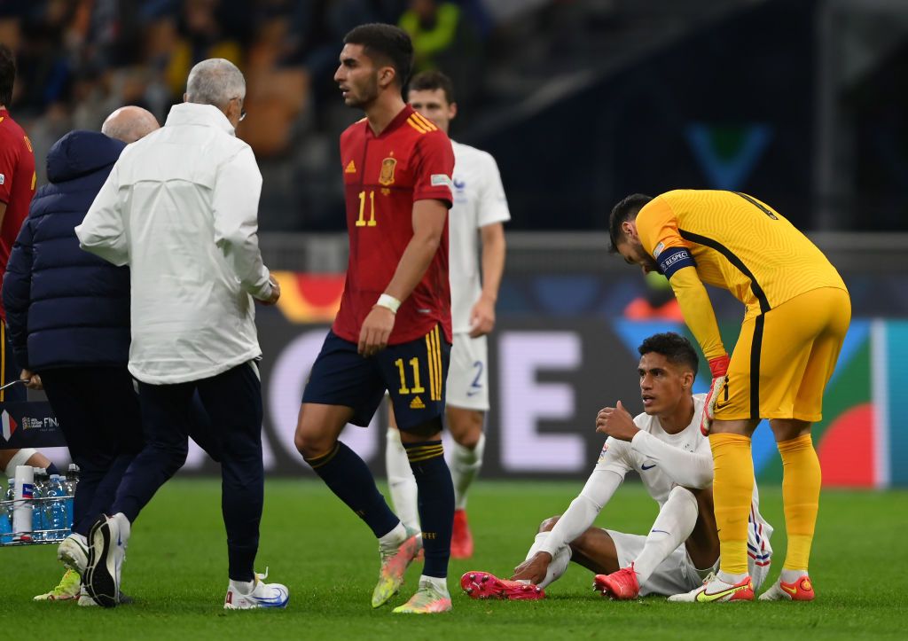 MILAN, ITALY - OCTOBER 10: Raphael Varane of France lies on the floor as they receive medical attention during the UEFA Nations League 2021 Final match between Spain and France at San Siro Stadium on October 10, 2021 in Milan, Italy. (Photo by Mike Hewitt/Getty Images)