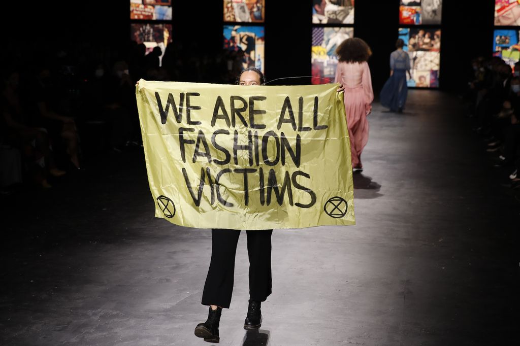 An activist displays a banner during Dior's Spring 2021 show.