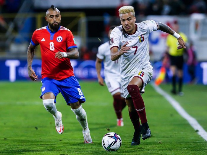 SANTIAGO, CHILE - OCTOBER 14: Adalberto Peñaranda of Venezuela drives the ball while followed by Arturo Vidal of Chile during a match between Chile and Venezuela as part of South American Qualifiers for Qatar 2022 at Estadio San Carlos de Apoquindo on October 14, 2021 in Santiago, Chile. (Photo by Claudio Reyes - Pool/Getty Images)