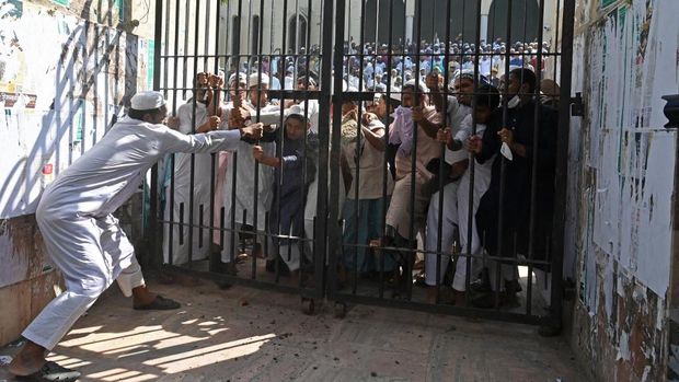 Protesters try to break a locked gate of the National Mosque during a demonstration after the Friday prayers in Dhaka on October 15, 2021, as protests began on October 13 after footage emerged of a Koran being placed on the knee of a figure of a Hindu god during celebrations for the Hindu festival of Durga Puja. (Photo by Munir Uz zaman / AFP)