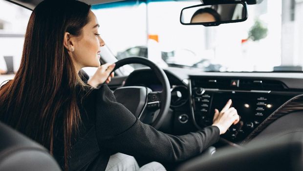 Young woman testing a car in a car showroom