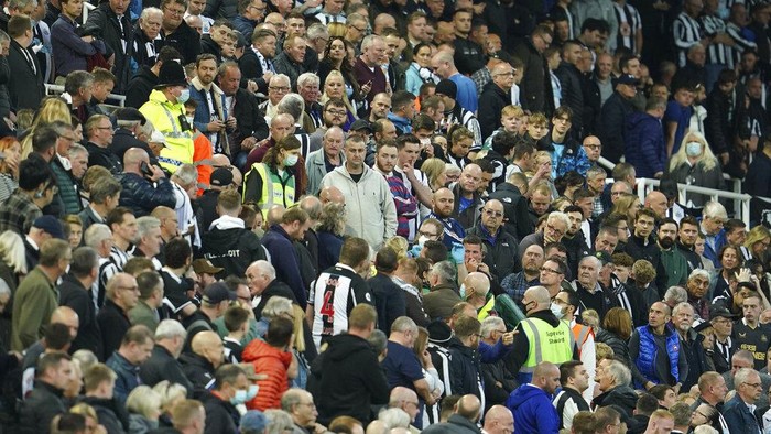 Fans stand around a person with a possible medical problem in the crowd during an English Premier League soccer match between Newcastle and Tottenham Hotspur at St. James Park in Newcastle, England, Sunday Oct. 17, 2021. (AP Photo/Jon Super)