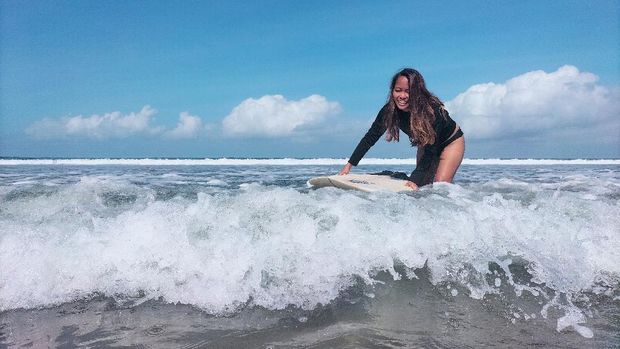 A surfing business owner, 38-year-old, Halfia Lando poses holding a surfboard at a Kuta beach as Indonesia opens up the tourist island of Bali to some countries including China, New Zealand, and Japan from October 14, visitors are still required to quarantine for eight days at their own expense, in Denpasar, Bali, Indonesia, October 12, 2021. REUTERS/Sultan Anshori NO RESALES. NO ARCHIVES