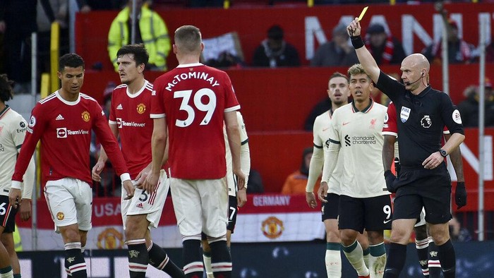 Referee Anthony Taylor shows a yellow card to Manchester Uniteds Cristiano Ronaldo, left, during the English Premier League soccer match between Manchester United and Liverpool at Old Trafford in Manchester, England, Sunday, Oct. 24, 2021. (AP Photo/Rui Vieira)