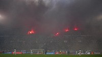 Petasan suar (flare) yang dinyalakan suporter menghadirkan asap di udara. (Foto: AP/Daniel Cole)