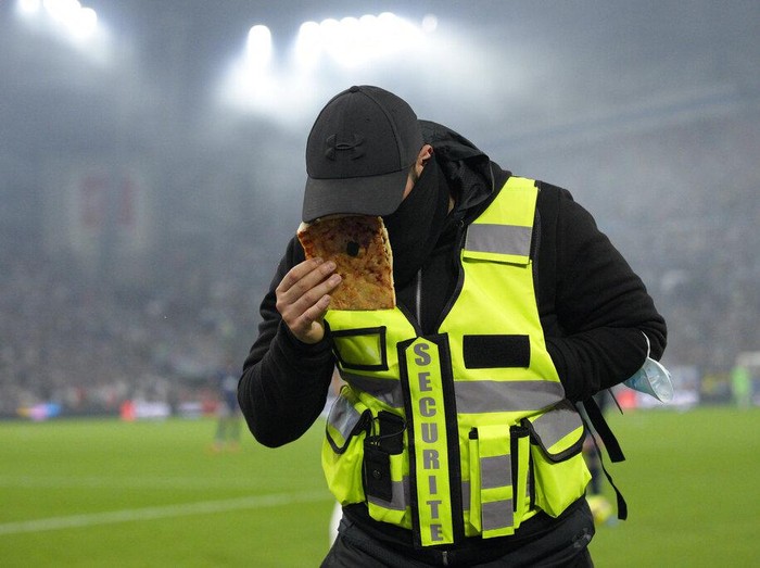 A member of security looks at a piece of pizza thrown from the crowd during the French League One soccer match between Marseille and Paris Saint-Germain in Marseille, France, Sunday, Oct. 24, 2021. (AP Photo/Daniel Cole)