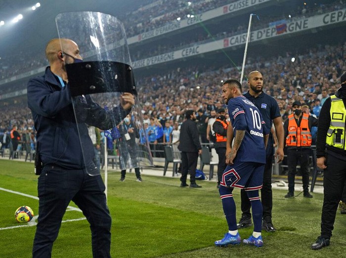 Shields are held up to protect PSG's Neymar from objects possibly being thrown as he goes to take a corner during the French League One soccer match between Marseille and Paris Saint-Germain in Marseille, France, Sunday, Oct. 24, 2021. (AP Photo/Daniel Cole)