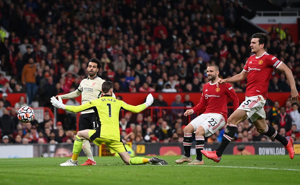 MANCHESTER, ENGLAND - OCTOBER 24:  Mohamed Salah of Liverpool shoots past Manchester United goalkeeper David De Gea to score his hat trick as Harry Maguire and Luke Shaw look on during the Premier League match between Manchester United and Liverpool at Old Trafford on October 24, 2021 in Manchester, England. (Photo by Shaun Botterill/Getty Images)
