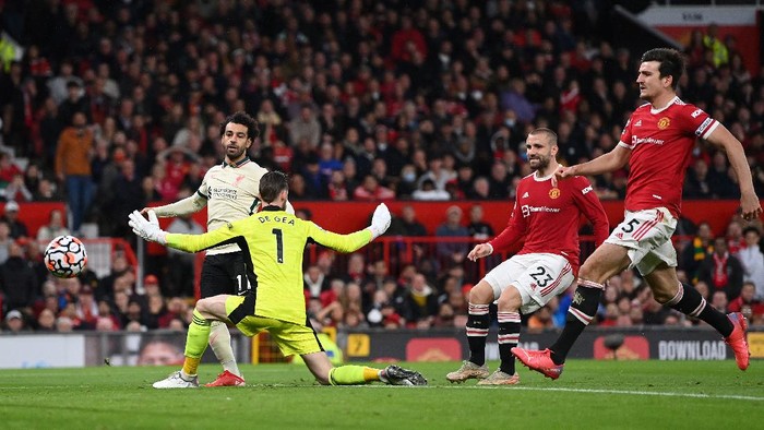 MANCHESTER, ENGLAND - OCTOBER 24:  Mohamed Salah of Liverpool shoots past Manchester United goalkeeper David De Gea to score his hat trick as Harry Maguire and Luke Shaw look on during the Premier League match between Manchester United and Liverpool at Old Trafford on October 24, 2021 in Manchester, England. (Photo by Shaun Botterill/Getty Images)