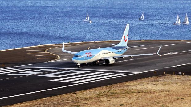 TUI Boeing 737. Pesawat jet komersial memulai sistem roda pendarat untuk mendarat. Bandara Funchal, Madeira, Portugal.  Samudera Atlantik.  12 Agustus 2018.