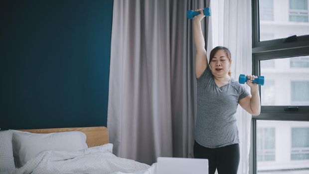 asian chinese body -positive woman workout with dumb bell online exercise class at home during weekend using laptop