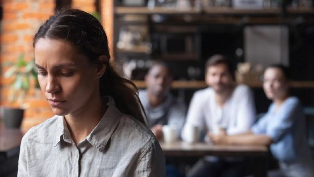 Upset mixed race woman suffering from bullying, discrimination, excluded girl having problem with bad friends, feeling offended and hurt, sitting alone in cafe, avoiding people, social outcast