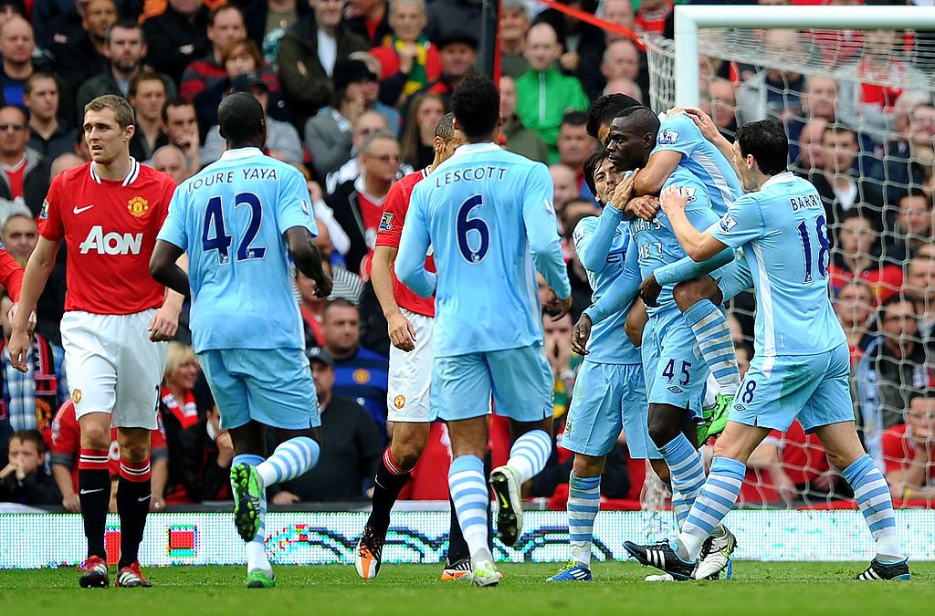 MANCHESTER, ENGLAND - OCTOBER 23:  Mario Balotelli of Manchester City is congratulated by his team mates after scoring the opening goal during the Barclays Premier League match between Manchester United and Manchester City at Old Trafford on October 23, 2011 in Manchester, England.  (Photo by Laurence Griffiths/Getty Images)
