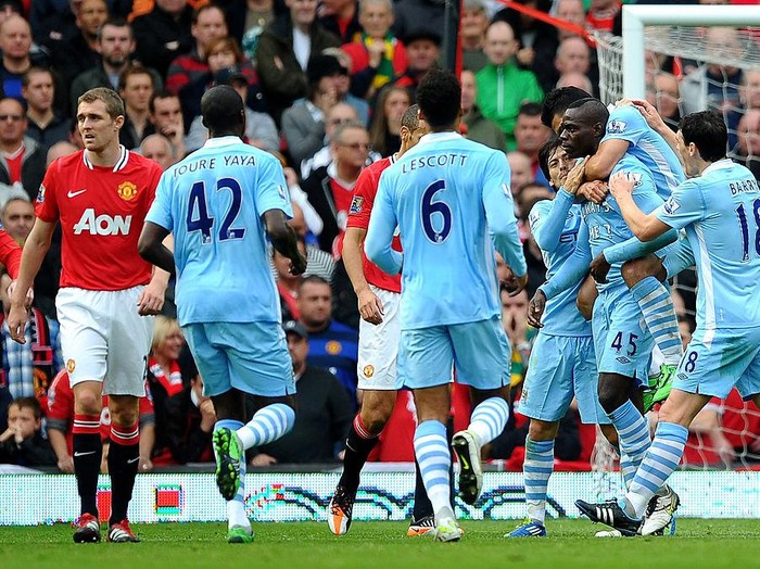 MANCHESTER, ENGLAND - OCTOBER 23:  Mario Balotelli of Manchester City is congratulated by his team mates after scoring the opening goal during the Barclays Premier League match between Manchester United and Manchester City at Old Trafford on October 23, 2011 in Manchester, England.  (Photo by Laurence Griffiths/Getty Images)