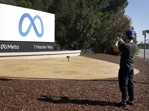 Facebook employees take a photo with the companys new name and logo outside its headquarters in Menlo Park, Calif., Thursday, Oct. 28, 2021, after the company announced that it is changing its name to Meta Platforms Inc. (AP Photo/Tony Avelar)