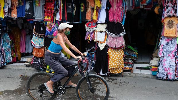 Warga negara asing (WNA) melintas di dekat kios pedagang di Pasar Seni Kuta, Badung, Bali, Jumat (15/10/2021). Aktivitas pasar seni tersebut masih sepi pengunjung meskipun pariwisata Bali untuk wisatawan mancanegara sudah dibuka pada Kamis (14/10/2021). ANTARA FOTO/Nyoman Hendra Wibowo/aww.