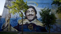 Warga melintas di depan mural Maradona di Ibu Kota Buenos Aires, Jumat, (29/10). Semasa hidup, Maradona bermain untuk timnas sebanyak 91 kali dengan koleksi 34 gol. (Natacha Pisarenko/AP Photo)