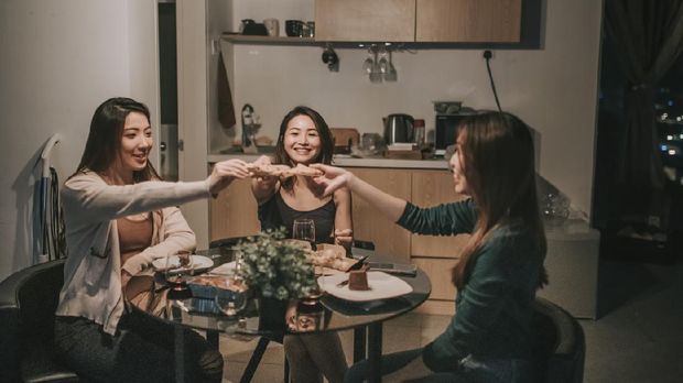 a group of asian chinese female friends having social gathering in apartment eating pizza in dining room at night
