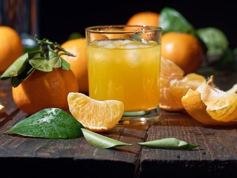 Tangerine juice in drinking glasses amid the tangerines lying on the table. Close-up