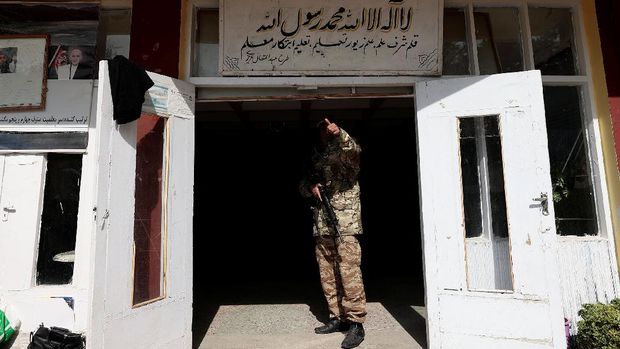 A Taliban fighter gestures to a colleague as he stands by the entrance to a school, in Kabul, Afghanistan, October 25, 2021. The hardline Islamist Taliban movement, which stormed to power earlier this year after ousting the Western-backed government, has allowed all boys and younger girls back to class, but has not let girls attend secondary school.  REUTERS/Zohra Bensemra     SEARCH 