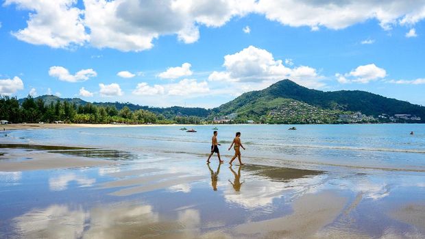 Tourists walk on a beach on the Thai island of Phuket on November 1, 2021, as Thailand welcomes the first group of tourists fully vaccinated against the Covid-19 coronavirus without quarantine. (Photo by Mladen ANTONOV / AFP)