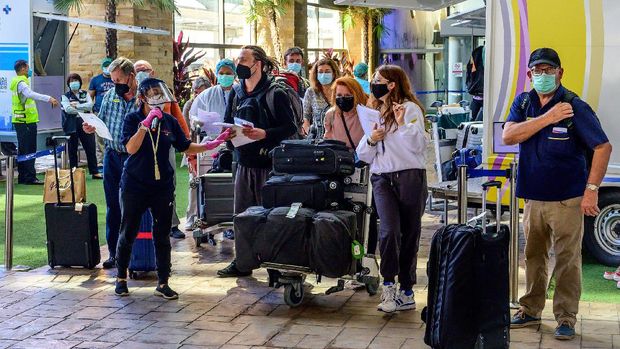 An airport employee assists passengers through the arrival area at Phuket International Airport as Thailand welcomes the first group of tourists fully vaccinated against the Covid-19 coronavirus without quarantine in Phuket on November 1, 2021. (Photo by Mladen ANTONOV / AFP)