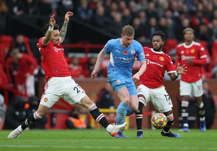 MANCHESTER, ENGLAND - NOVEMBER 06:  Kevin De Bruyne of Manchester City runs with the ball from Alex Telles and Fred of Manchester United during the Premier League match between Manchester United and Manchester City at Old Trafford on November 06, 2021 in Manchester, England. (Photo by Clive Brunskill/Getty Images)