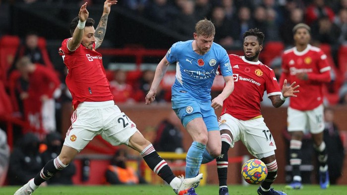 MANCHESTER, ENGLAND - NOVEMBER 06:  Kevin De Bruyne of Manchester City runs with the ball from Alex Telles and Fred of Manchester United during the Premier League match between Manchester United and Manchester City at Old Trafford on November 06, 2021 in Manchester, England. (Photo by Clive Brunskill/Getty Images)