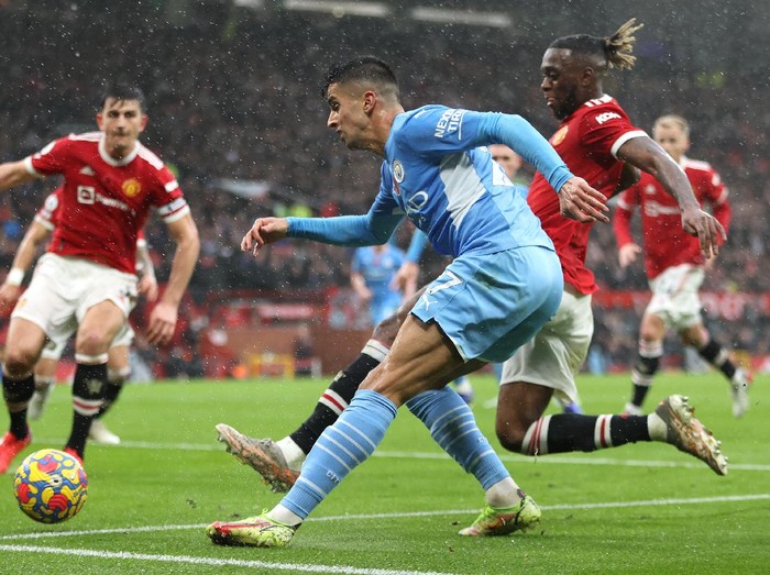 MANCHESTER, ENGLAND - NOVEMBER 06: Joao Cancelo of Manchester City crosses the ball whilst under pressure from Aaron Wan-Bissaka of Manchester United  during the Premier League match between Manchester United and Manchester City at Old Trafford on November 06, 2021 in Manchester, England. (Photo by Clive Brunskill/Getty Images)