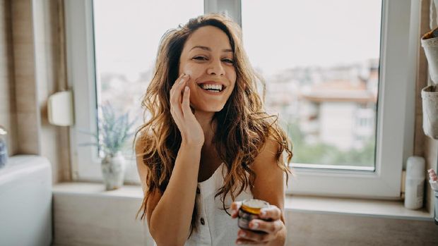 Young woman applies facial cream