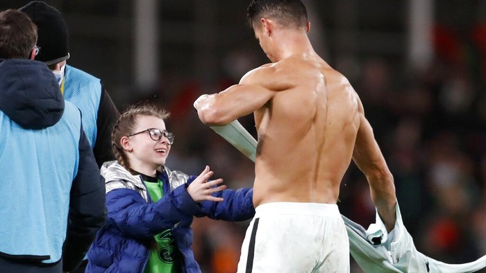 Aksi Manis Ronaldo Kasih Jersey untuk Fans Ciliknya Portugal's Cristiano Ronaldo gives his shirt to a young fan who walked on to the pitch at the end of the World Cup 2022 group A qualifying soccer match between the Republic of Ireland and Portugal at the Aviva stadium in Dublin, Thursday, Nov. 11, 2021. The game ended in a goalless draw. (AP Photo/Peter Morrison)