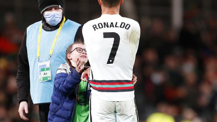 Aksi Manis Ronaldo Kasih Jersey untuk Fans Ciliknya Portugal's Cristiano Ronaldo gives his shirt to a young fan who walked on to the pitch at the end of the World Cup 2022 group A qualifying soccer match between the Republic of Ireland and Portugal at the Aviva stadium in Dublin, Thursday, Nov. 11, 2021. The game ended in a goalless draw. (AP Photo/Peter Morrison)