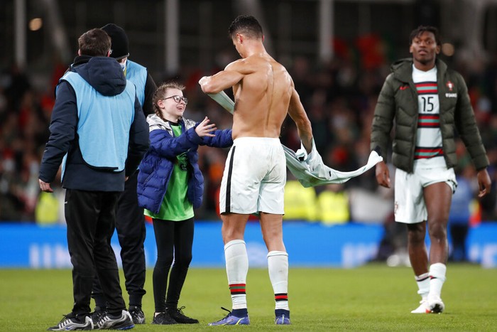 Aksi Manis Ronaldo Kasih Jersey untuk Fans Ciliknya Portugal's Cristiano Ronaldo gives his shirt to a young fan who walked on to the pitch at the end of the World Cup 2022 group A qualifying soccer match between the Republic of Ireland and Portugal at the Aviva stadium in Dublin, Thursday, Nov. 11, 2021. The game ended in a goalless draw. (AP Photo/Peter Morrison)