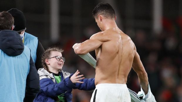 Portugal's Cristiano Ronaldo gives his shirt to a young fan who walked on to the pitch at the end of the World Cup 2022 group A qualifying soccer match between the Republic of Ireland and Portugal at the Aviva stadium in Dublin, Thursday, Nov. 11, 2021. The game ended in a goalless draw. (AP Photo/Peter Morrison)