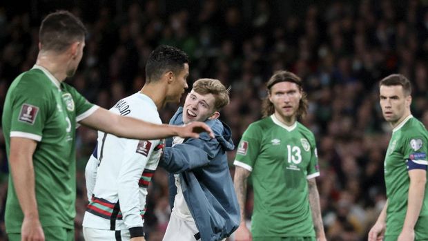 A pitch invader tries to reach Portugal's Cristiano Ronaldo, 2nd left, during the World Cup 2022 group A qualifying soccer match between the Republic of Ireland and Portugal at the Aviva stadium in Dublin, Thursday, Nov. 11, 2021. (AP Photo/Peter Morrison)