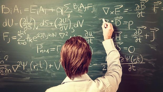 Newton's Equations. Rear view, close-up on young man standing back against green chalkboard. He explains, solves physics tasks, retro style. Processing for retro bleached look, slight vignette added.