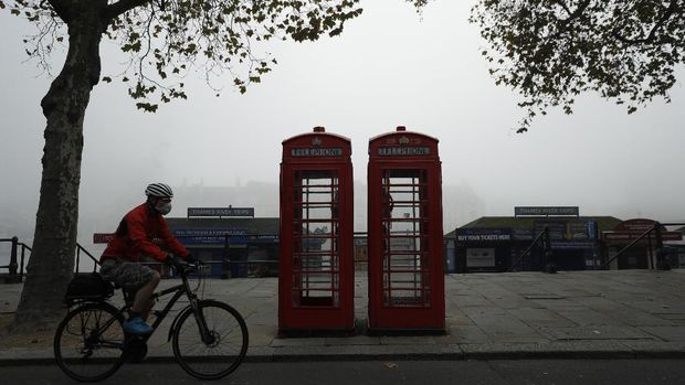 A cyclist wearing a face mask passes traditional red phone boxes, on the first day of Britain's second lockdown designed to save its health care system from being overwhelmed by people with coronavirus, in London, Thursday, Nov. 5, 2020. Britain joined large swathes of Europe in a coronavirus lockdown designed to save its health care system from being overwhelmed. Pubs, along with restaurants, hairdressers and shops selling non-essential items closed on Thursday until at least Dec. 2. (AP Photo/Matt Dunham)