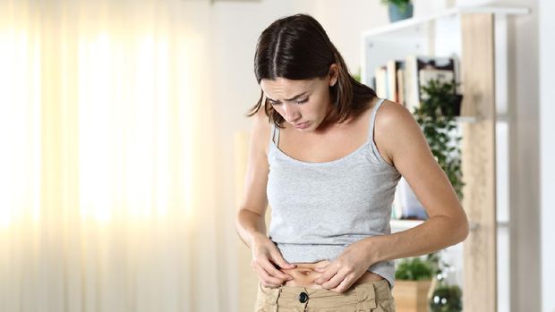 Woman worried about body fat touching her belly