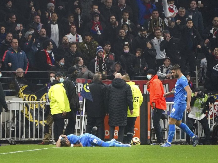 Marseille's Dimitri Payet reacts after being injured by an object thrown by a Lyon's supporter during the French League One soccer match between Lyon and Marseille, in Decines, near Lyon, central France, Sunday, Nov. 21, 2021. (AP Photo/Laurent Cipriani)