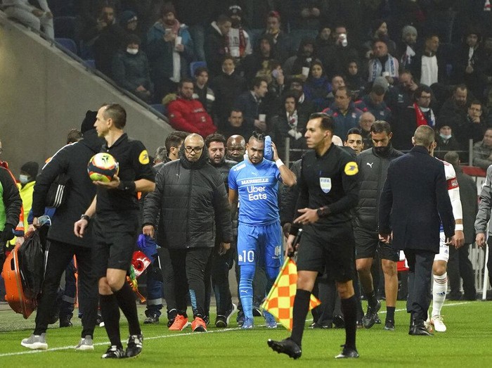 Marseille's Dimitri Payet, center, is surrounded by his staff as he leaves the field after being injured by an object thrown by a Lyon's supporter during the French League One soccer match between Lyon and Marseille, in Decines, near Lyon, central France, Sunday, Nov. 21, 2021. (AP Photo/Laurent Cipriani)