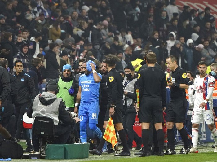 Marseille's Dimitri Payet, center, is surrounded by his staff as he leaves the field after being injured by an object thrown by a Lyon's supporter during the French League One soccer match between Lyon and Marseille, in Decines, near Lyon, central France, Sunday, Nov. 21, 2021. (AP Photo/Laurent Cipriani)