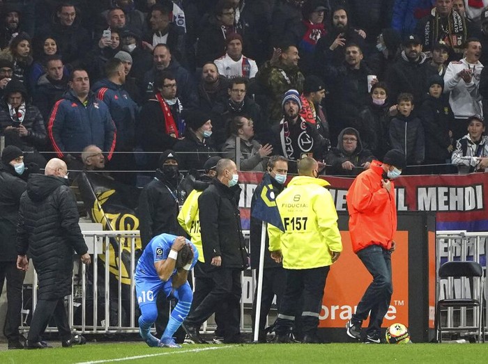 Marseille's Dimitri Payet reacts after being injured by an object thrown by a Lyon's supporter during the French League One soccer match between Lyon and Marseille, in Decines, near Lyon, central France, Sunday, Nov. 21, 2021. (AP Photo/Laurent Cipriani)