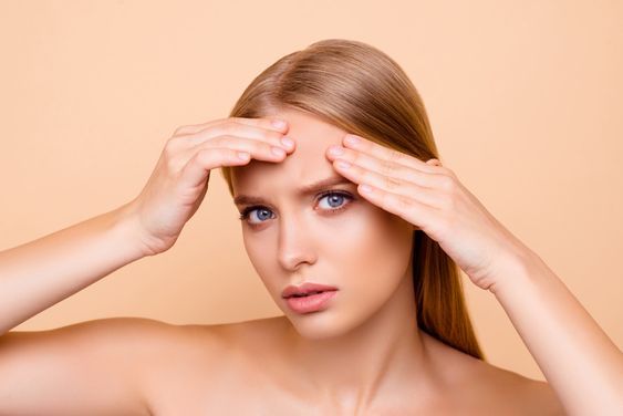 Perempuan yang melihat jerawat di wajahnya saat bercermin/Pinterest from Bovary