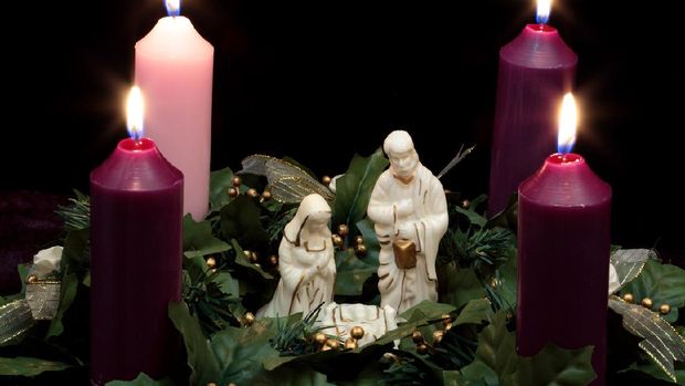 Advent wreath with Nativity scene in the middle of 4 burning candles and holly greenery. Horizontal image would be good for Christian or religious Christmas use. I have a vertical image of this also.