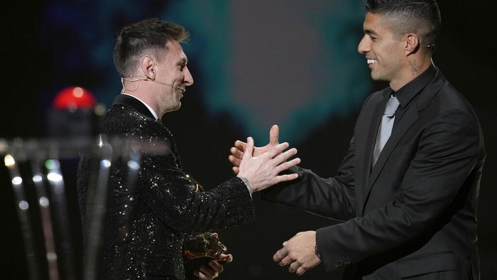 PSG player Lionel Messi receives the 2021 Ballon dOr trophy from his former Barcelona teammate Luis Suarez during the 65th Ballon dOr ceremony at Theatre du Chatelet, in Paris, Monday, Nov. 29, 2021. (AP Photo/Christophe Ena)