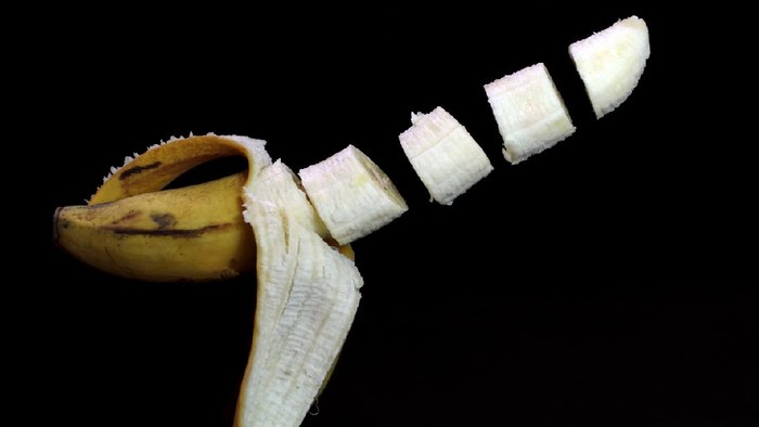 1220494935 banana with open skin in the tossed state on a dark background fraktur penis